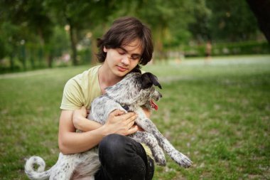 Evlatlık köpeği olan bir çocuğun açık hava portresi. Evcil hayvanlarla arkadaşlık, yaz otlaklarında yürüyen çocuk manzaralı günbatımı manzaraları. Yüksek kalite fotoğraf