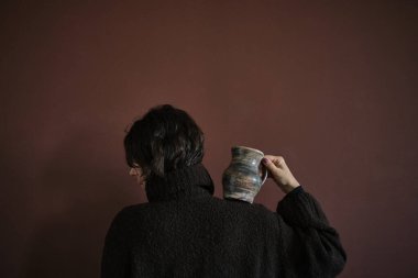 Önlüklü, el yapımı çömlek taşıyan genç bir kadın. Eski tip akrabalık kavramı. Gösterişsiz kusurlu fotoğraf. Minimalizm Yüksek kalite fotoğraf