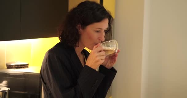 オフィスキッチンでコーヒーマシンからコーヒーを飲む若いビジネス女性 暗いビジネススーツを着た女性 高品質4K映像 — ストック動画