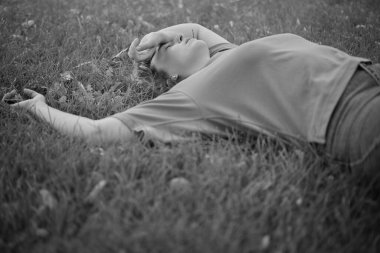 Doğada yazın bir parkta çimlerin üzerinde uzanan mutlu bir kadının portresi. Bahçe ve kadın ya da açık hava modeli özgürlük, mutluluk, tarz. Yüksek kalite fotoğraf