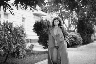 Genç, modaya uygun, modaya uygun, güzel, sıradan bir kadın sırt çantasıyla şehir caddesinde yürüyor. Kadın portresi, buluşmak için acele eden kot pantolon ve trençkot giyiyor. Yüksek kalite fotoğraf