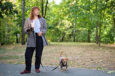 Sahibi köpekle birlikte parkta geziyor, yaz tatili, sevimli evcil hayvan konsepti insanlarla evcil hayvanları arasında arkadaşlık. Süveter giyen Dachshund Yüksek kalite fotoğraf