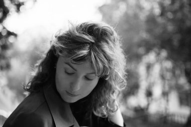 Beyaz, olgun, güzel bir kadının yakın plan portresi. Parkta güneşe bakıyor. Gün batımından saklanıyor. Yüksek kalite fotoğraf