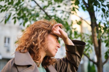 Beyaz, olgun, güzel bir kadının yakın plan portresi. Parkta güneşe bakıyor. Gün batımından saklanıyor. Yüksek kalite fotoğraf