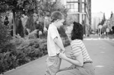 Sevimli anne ve oğul gülümsüyor. Şehir arka planında eğleniyorlar. Annelik kavramı, sarılma. 8 yaşında parlak elbiseli bir çocukla annesi yaz gününün tadını çıkarıyor. Yüksek kalite fotoğraf