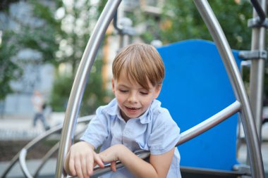 Güneşli şehir geçmişinde güzel gülümseyen küçük bir çocuk. Yakın plan portre. Sarı saçlı, mavi gözlü, 9 yaşında gülümseyen, şehirde eğlenen bir çocuk. Yüksek kalite fotoğraf