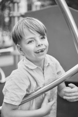 Güneşli şehir geçmişinde güzel gülümseyen küçük bir çocuk. Yakın plan portre. Sarı saçlı, mavi gözlü, 9 yaşında gülümseyen, şehirde eğlenen bir çocuk. Yüksek kalite fotoğraf