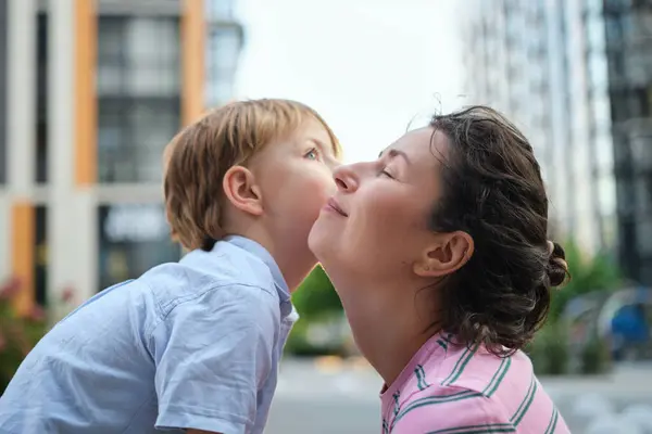 stock image Adorable mother and son smiling happy having fun at city background. Motherhood concept, hugging. Boy 8 years old with mother in bright clothes enjoying summer day. High quality photo