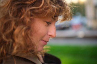 Kameraya bakan mutlu olgun bir kadının portresi. Gün batımında şehir sokağında başarılı bir gururlu kadın. Açık havada gülümseyen resmi giysili beyaz kadın. Yüksek kalite fotoğraf