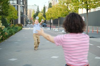 Küçük oğlan sarılmak için annesine koşuyor. Anne ve küçük çocuk parkta dışarıda oynuyorlar. Mutlu aile kavramı. Yüksek kalite fotoğraf