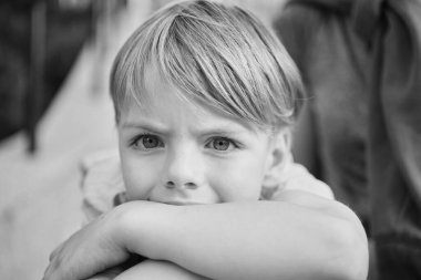 Güneşli şehir geçmişinde güzel gülümseyen küçük bir çocuk. Yakın plan portre. Sarı saçlı, mavi gözlü, 9 yaşında gülümseyen, şehirde eğlenen bir çocuk. Yüksek kalite fotoğraf