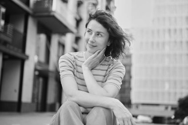 Dışarıda yürüyen mutlu genç bir kadın. Kendine güvenen bir kız sokakta gülümsüyor. Şehir merkezi, konut kompleksi, emlak konsepti. Pembe elbiseli esmer bir kadın. Yüksek kalite fotoğraf