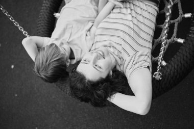 Mutlu genç anne oğluyla parkta oynuyor, sarılıyor, gülüyor. Güneşli bir hafta sonunda birlikte eğleniyoruz. Okul bahçesinde. Yüksek kalite fotoğraf