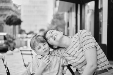 Genç anne ve oğlu yaz günü açık hava restoranında tatlı yiyorlar. Birlikte oturuyoruz, sarılıp gülüyoruz, hafta sonunun tadını çıkarıyoruz. Yüksek kalite fotoğraf