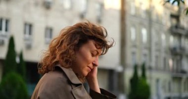 Beyaz, olgun, tapılası bir kadının portresi. Güneşin şehrin arka planında durup neşeli bir şekilde güneşe bakıyor. İş kadını ya da kendinden emin prson konsepti