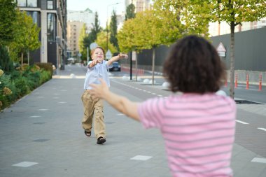 Küçük oğlan sarılmak için annesine koşuyor. Anne ve küçük çocuk parkta dışarıda oynuyorlar. Mutlu aile günü konsepti