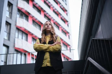 Ofis binasının arka planında güzel sarışın bir ofis çalışanı. Pozitif duygular, sarı gömlek ve ceket giyiyor. Yüksek kalite fotoğraf