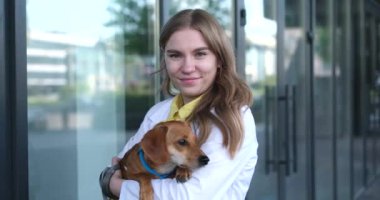 Veteriner kliniğinin girişinde gülümseyen ve köpeği tutan genç bir veteriner. Sağlıklı köpek, teşhis, evcil hayvan tedavisi. video görüntüleri 4k