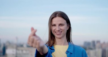 Ukrayna 'nın ulusal renkleri içinde genç bir kadın Kyiv şehrinin manzarasına sevgi yolluyor. Bağımsız kavram, Ukrayna 'yı desteklemek, savaşı durdurmak. Yüksek kalite fotoğraf