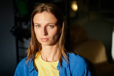 Ukrayna 'nın ulusal renkleri giymiş genç bir kadın gün batımında evde. Bağımsız kavram, Ukrayna 'yı desteklemek, savaşı durdurmak. Yüksek kalite fotoğraf