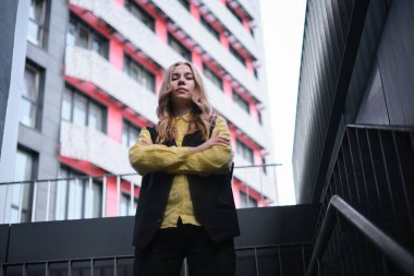 Ofis binasının arka planında güzel sarışın bir ofis çalışanı. Pozitif duygular, sarı gömlek ve ceket giyiyor. Yüksek kalite fotoğraf