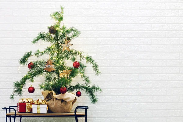 白レンガの壁の背景に贈り物とヴィンテージクリスマスツリー — ストック写真