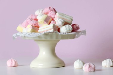 Vase with sweets on a pink background