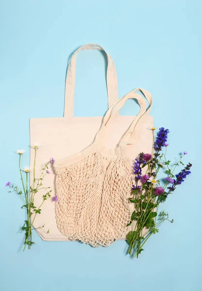 Beige cotton tote  and string bags with wildflowers on a light blue background