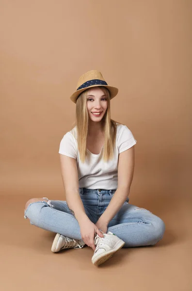 ベージュの背景に帽子を持つかなり若い女性の肖像画 — ストック写真