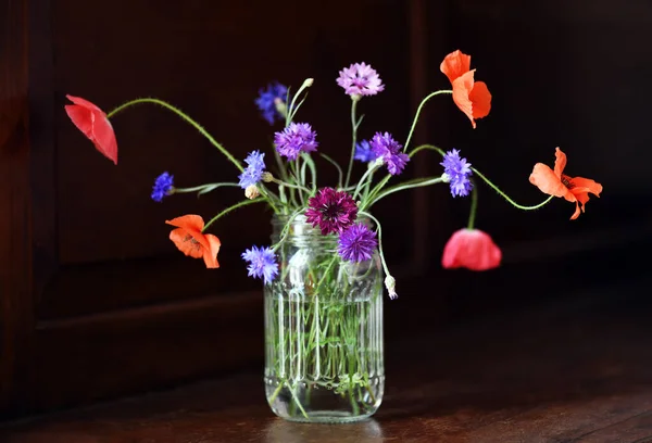 Ahşap Zemin Üzerinde Gelincikler Çiçek Olan Bir Cam — Stok fotoğraf