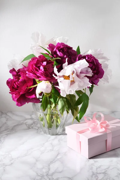 大理石のテーブルの上に贈り物と美しい牡丹の花束 — ストック写真