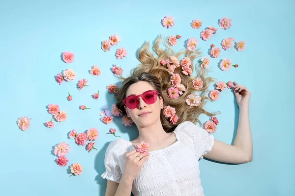 Красива Блондинка Лежить Багатьма Рожевими Трояндами Блакитному Фоні — стокове фото