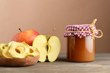 Reçel kavanozu, elmalı tabak ve bej arkaplanda taze elmalar.