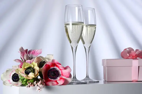 两杯香槟酒 礼物和鲜花 背景明亮 图库图片