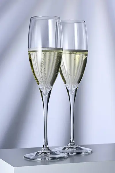 照らされた背景にシャンパンが付いている2つのガラス ロイヤリティフリーのストック画像