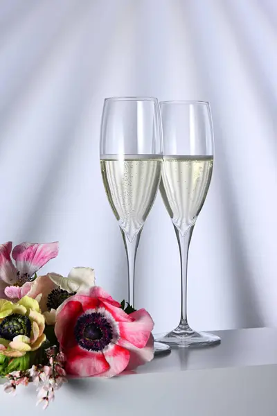 Dvě Sklenice Šampaňským Květinami Osvětleném Pozadí Royalty Free Stock Fotografie