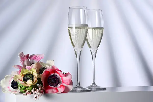 照らされた背景にシャンパンと花が付いた2つのメガネ ストック画像