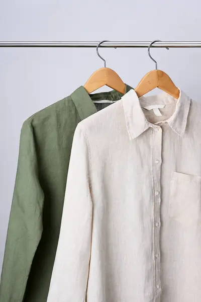 衬里米黄色和绿色衬衫挂在木制衣架上 免版税图库图片