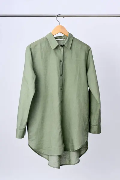 挂在木制衣架上的亚麻绿色衬衫 免版税图库图片
