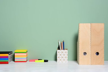 Yeşil duvar arka planında ofis aksesuarları olan masa