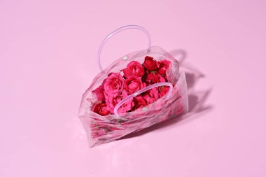 Pembe arka planda güzel güller olan şeffaf çanta.