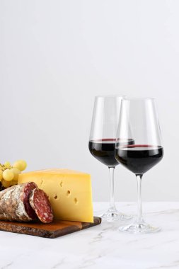 İki kadeh kırmızı şarap, üzümlü pansiyon, İtalyan peyniri ve salam. 
