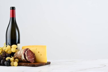 Bir şişe kırmızı şarap, üzümlü pansiyon, İtalyan peyniri ve salam.