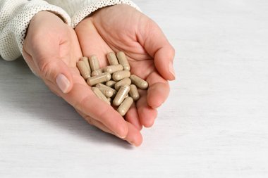 Bitkisel kapsülleri olan kadın elleri yakın plan.