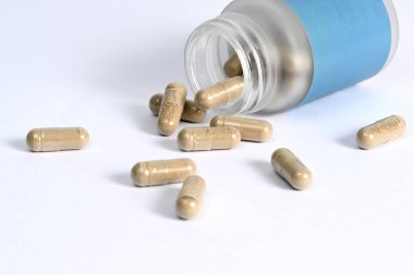 Beyaz arka planda bitkisel kapsülleri olan cam kavanoz