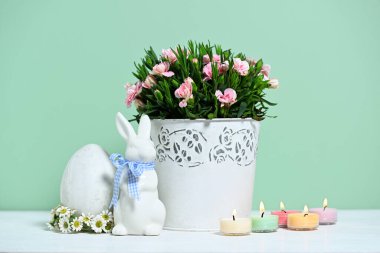 Paskalya kompozisyonu pembe karanfilli, dekoratif yumurtalı ve tavşanlı.
