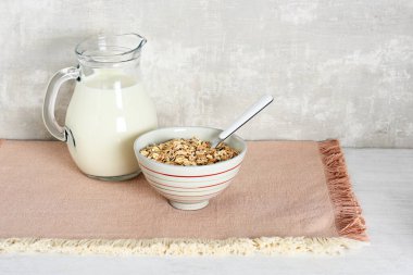 Yulaf gevreğiyle kase, pembe masa örtüsüyle sürahi.