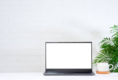 Beyaz ekranlı, beyaz ekranlı, beyaz tuğla duvarlı bir dizüstü bilgisayar.