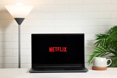 Piazza Brembana, İtalya 25 Nisan 2025 Netflix logosu olan dizüstü bilgisayar lambayla aydınlatılmış beyaz tuğla duvara karşı