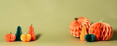 Autumnal composition of paper pumpkins on green background
